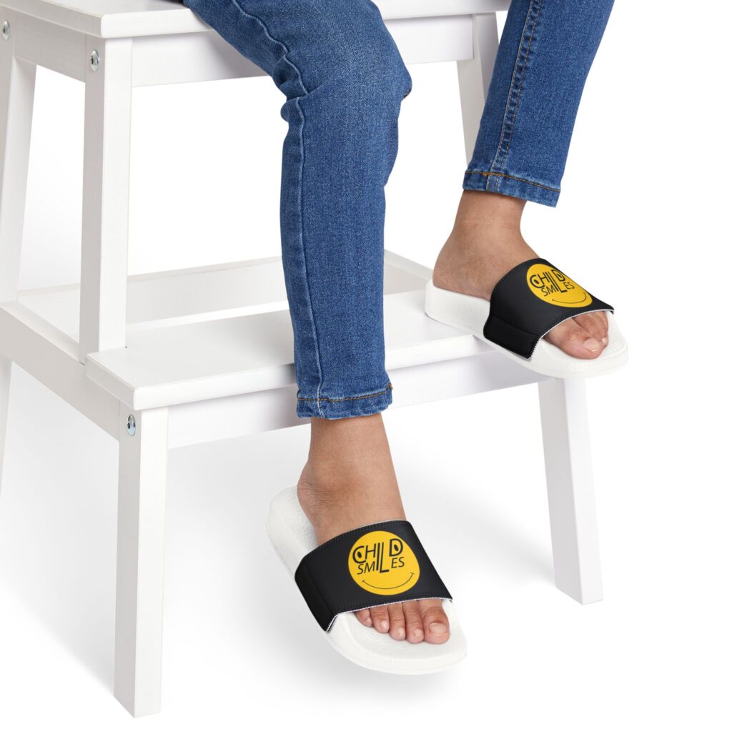 youth slide sandals — black strap with yellow "child smiles" logo